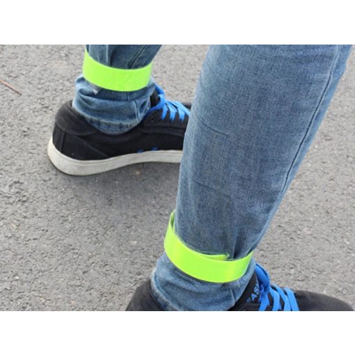 Jól látható, neon színű, önzáródó fényvisszaverő karpánt csuklón viselve sötétben.